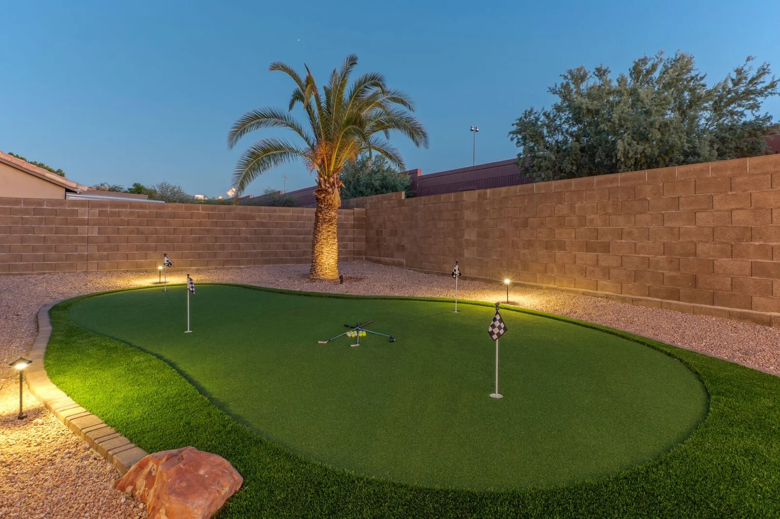 Private putting green with palm tree at dusk