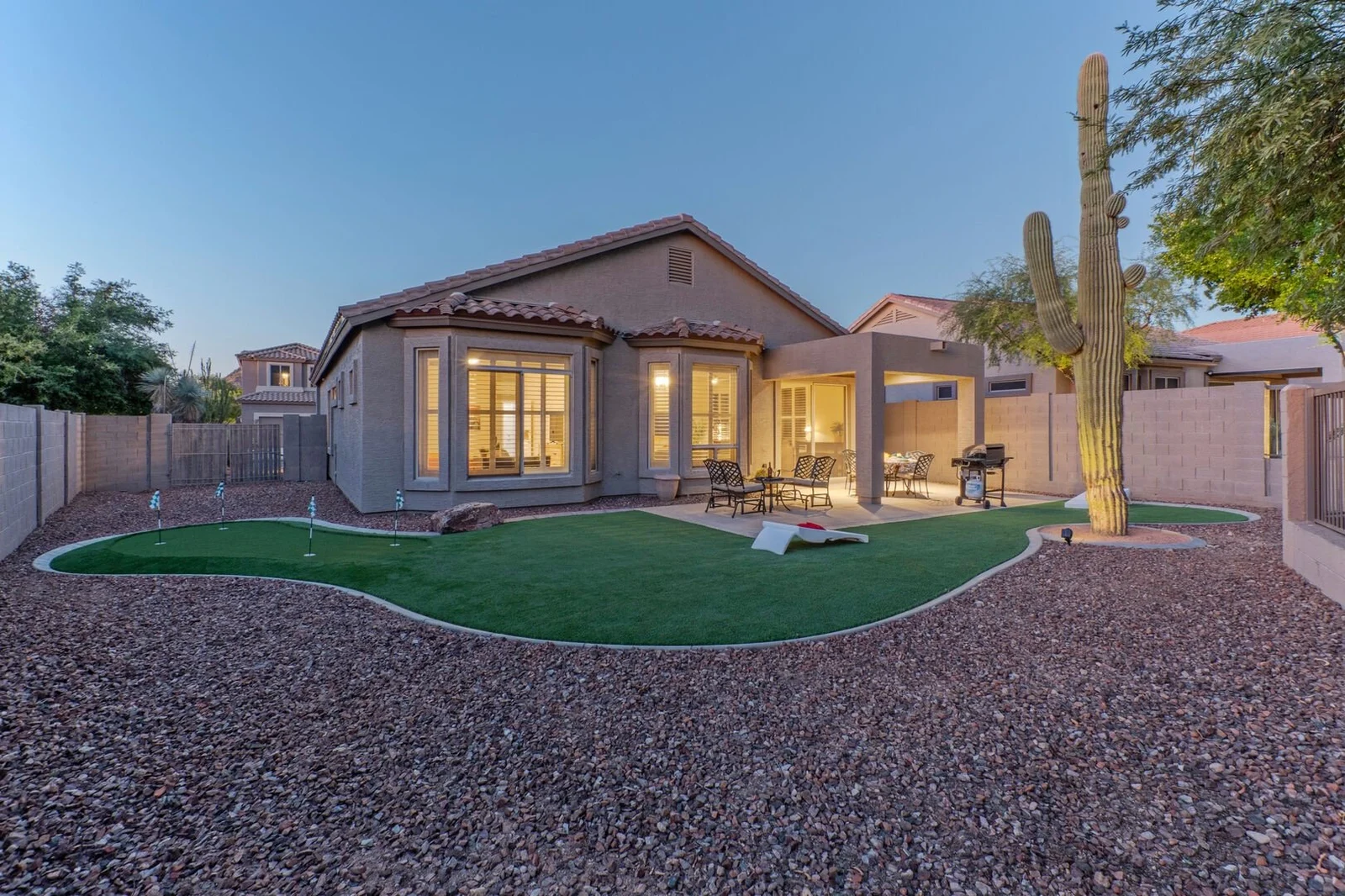 Desert home exterior at dusk with private putting green and saguaro cactus